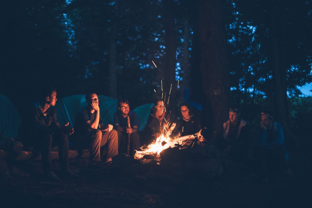 Seven people sitting around a bonfire