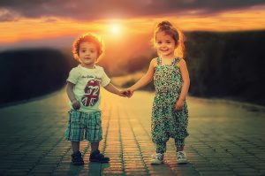 two children holding hands on a brick road