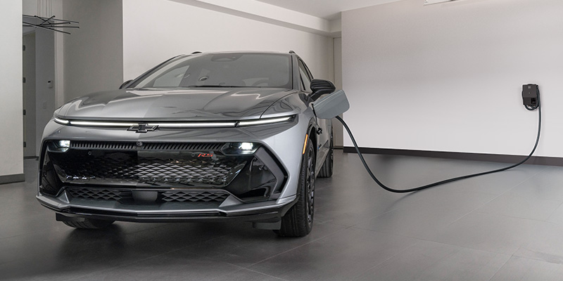 silver Chevrolet Equinox EV charging in a modern, minimalist white garage.