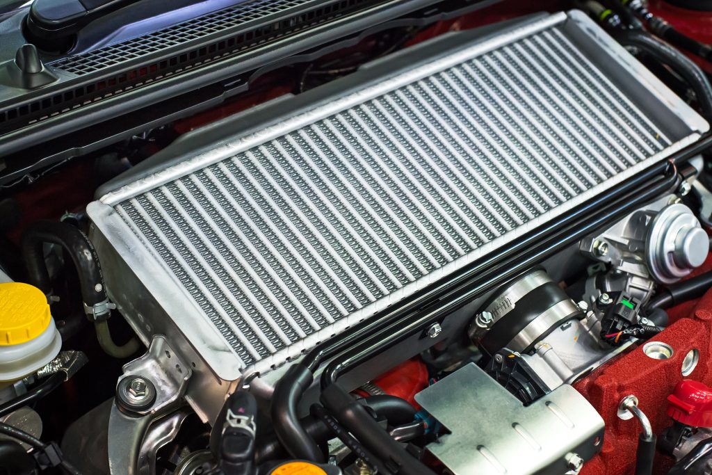 A high-angle, close-up view of a silver top-mount intercooler installed within a clean, performance-oriented car engine bay.