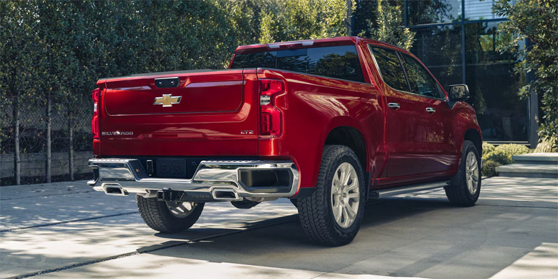 Rear-angle view of a cherry red Chevrolet Silverado LTZ parked on a driveway.